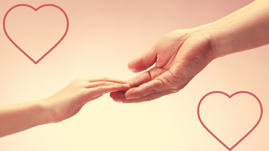 An adult hand reaching down with love to hold the hand of a young child.